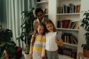 A teacher and two students taking a selfie inside a library, enjoying a happy moment together.